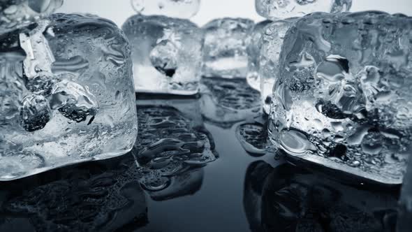 Ice Melting, Camera Moving Through Ice Cubes and Puddles of Water on Black Background, Extreme Heat