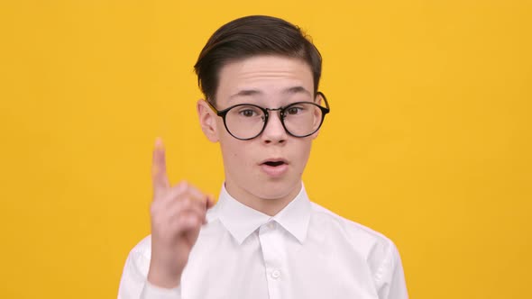 Schoolboy Pointing Finger Up Having Idea Over Yellow Studio Background