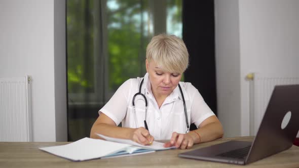 The Blonde Concentrated Women Physician is Checking the Data About Patients