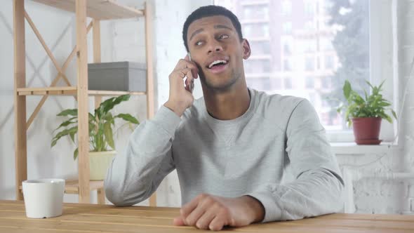 AfroAmerican Man Talking on Phone Attending Phone Call at Work