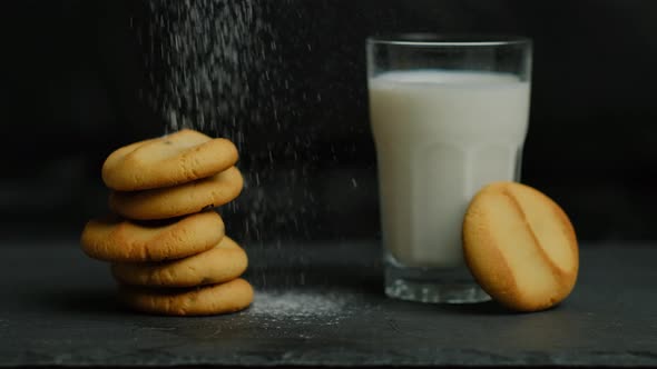 Homemade cookies with chocolate and icing sugar with milk on a black background