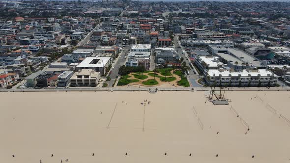 Aerial view overlooking the Hermosa cityscape and waves hitting the beach, in sunny Los Angeles, USA