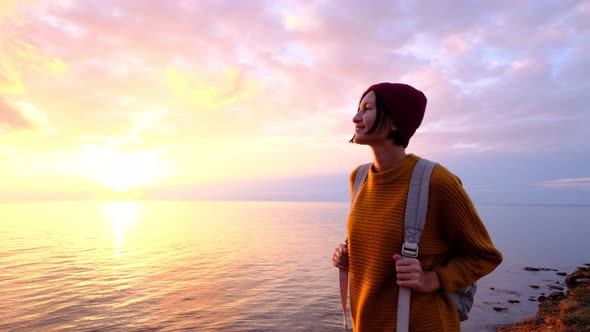 Young GoodLooking Woman Wearing Red Hat and Yellow Sweater and Slowly Approaching Ocean