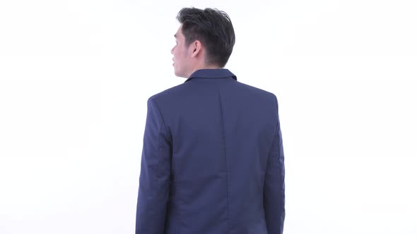 Rear View of Young Asian Businessman Thinking and Looking Around