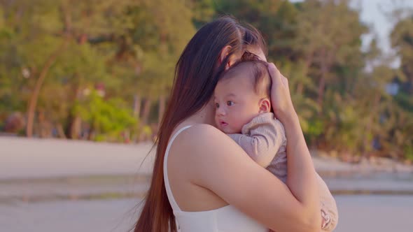 A young Asian mother is on the beach with her baby in summer time