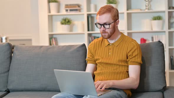 Redhead Man Celebrating Success on Laptop at Home 