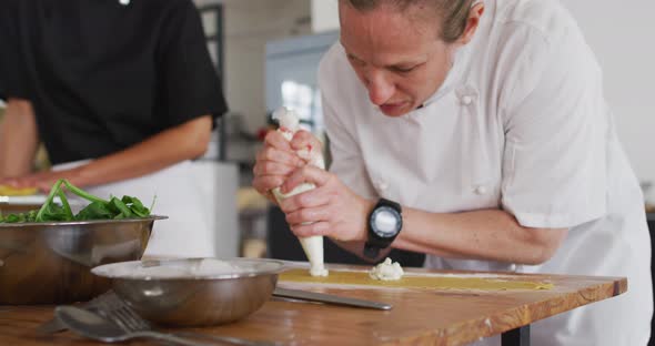 Caucasian female chef teaching diverse group preparing dishes and smiling