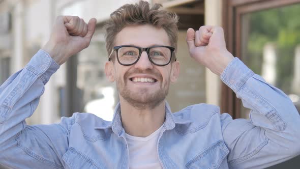 Casual Young Man Celebrating Success while Standing Outdoor