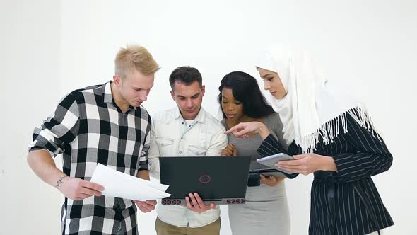 Serious Multiethnic Agreeable Office Workers Looking at the Computer and Discussing Project Details