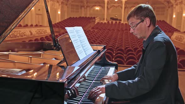 Pianist in Dark Suit Playing on a Grand Piano on Big Stage in Concert Hall