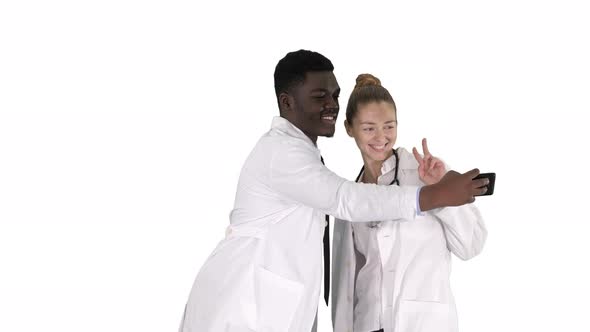 Two Doctors Are Making Selfie Using a Smartphone and Smiling on White Background.