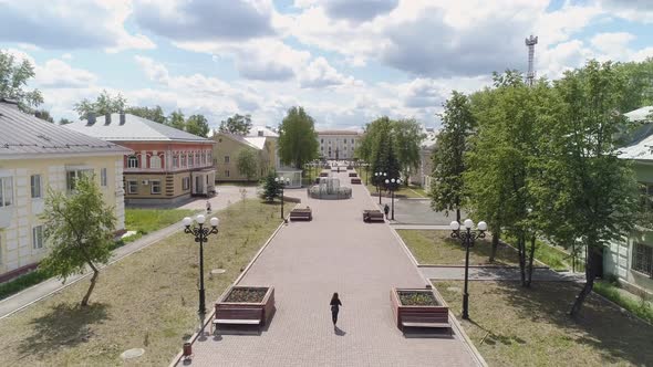 Girl walks along a beautiful alley in a provincial town. Back view 09