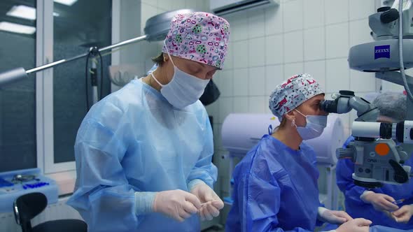 Patient under surgical microscope. Doctor with assistants doing eye surgery with modern microscope a