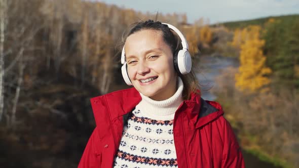 Caucasian Woman Stands on Hill in White Headphones and Dances