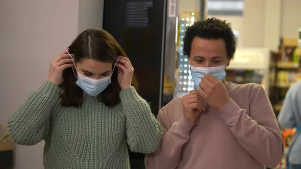 Multiethnic Couple Putting on Masks in Supermarket