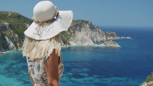 Blond Woman Wearing Sun Hat is Looking at Beautiful Sea Bay Enjoying Scenic Landscape on Vacation