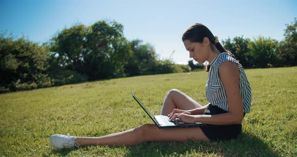 Freelance Woman Working with Laptop and Receiving Mobile Phone Call Outdoors