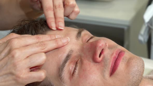 Cropped Shot of a Professional Masseuse Massaging Forehed of Male Client alt