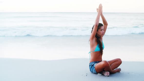 Woman performing yoga on beach