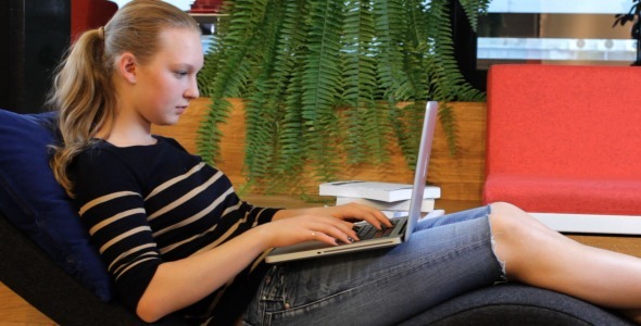 Young Female Student Using Laptop in Lounge Room