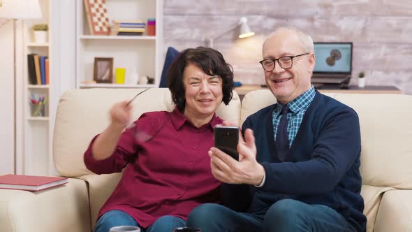 Old Man and Woman Having a Video Call Using Their Smartphone