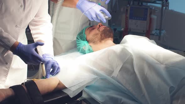 Male Assistants Prepares a Patient To Invasive Surgery in the Hospital Operating