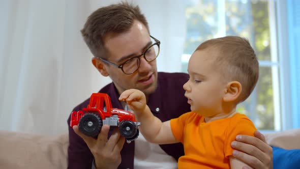 Smiling Young Father Playing Favorite Toy Car with Little Boy