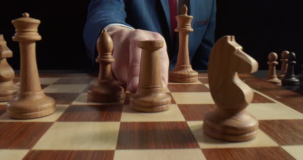 Close Up of Man Playing Chess and Making Move with White Rook Isolated on Black Background