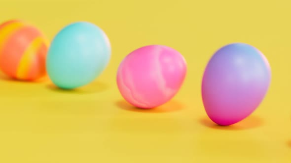 Cute multicolour Easter eggs rolling on a yellow background. Happy Easter. Joy.