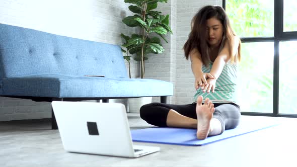 20s Young Asian Woman Watching Stretching Training Class on Computer Laptop Online in Living Toom