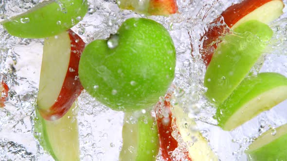 Super Slow Motion Shot of Red and Green Apple Cuts Falling and Splashing Into Water at 1000Fps