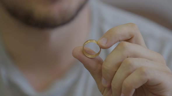 Portrait of Unrecognized Bearded Man Holding Golden Wedding Ring Sitting at Home