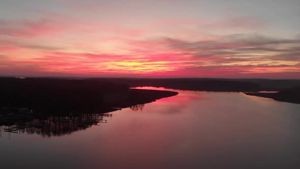 Rotating drone footage of a stunning sunset with a lake and forests on each side. Filmed in realtime