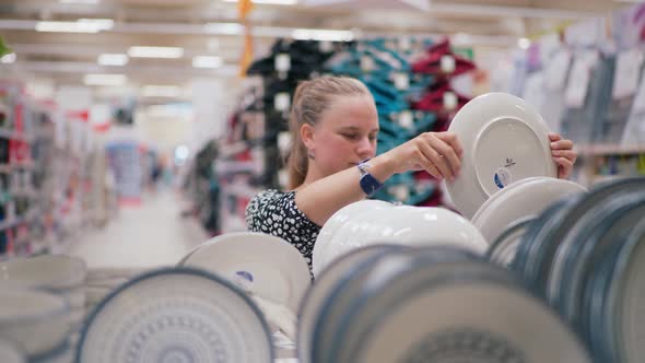 Young Girl Chooses Plates in the Shop