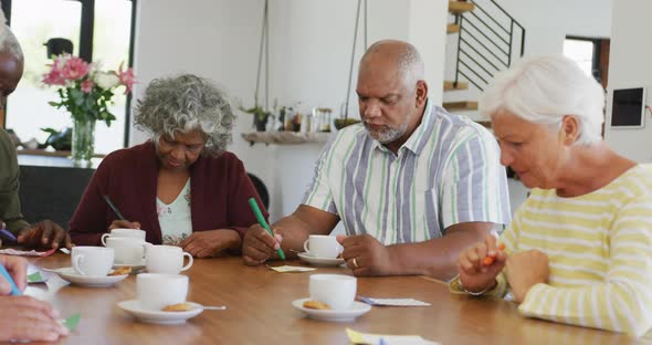 Happy senior diverse people drinking tea and playing bingo at retirement home