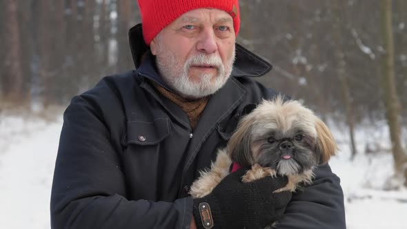 Bearded Pensioner Walks Along Snowy Road Holding Dog