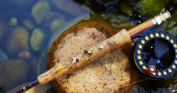 Fly fishing rod, reel and hook on rock