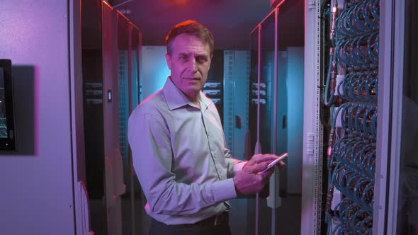 Middle-Aged Man in Server Room of Data Center