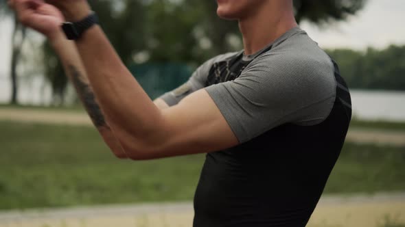 A close-up view of a muscular guy is doing exercises moving hands