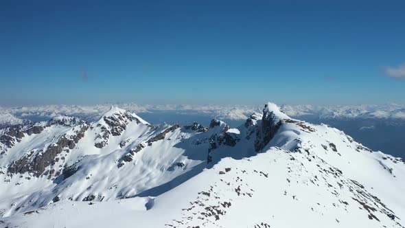 Aerial dolly in flying over snow capped peak at Piltriquitron Hill, mountains in background, El Bols