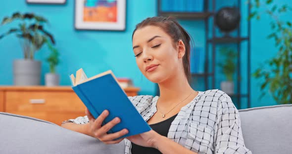 Young Women with Hair Pinned Up Relaxes in Homely Attire While Delving Into Book That