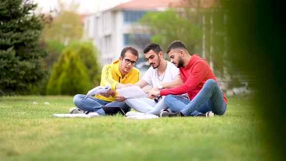 Three university students sitting on grass, writing articles, literary studies project