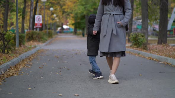 Mother and Son in Medical Masks Walk in the Park