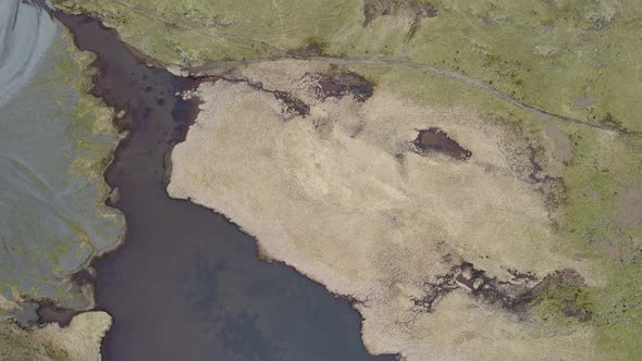 Flying over the brown sediment filled water pools on the edge of the Eldhraun Lava field