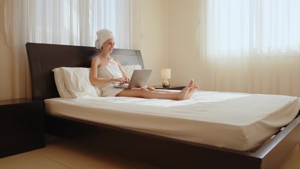 Lady in Bath Towel Using Laptop for Video Call at Hotel Room