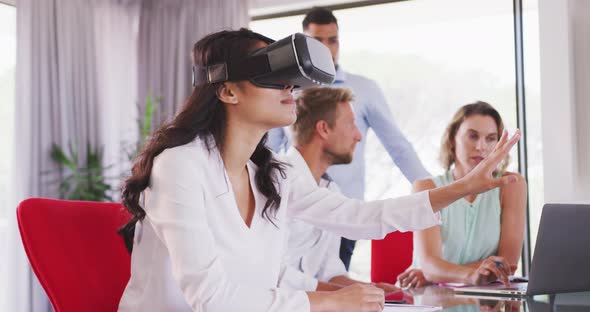 Professional businesswoman using virtual reality headset while sitting in office in slow motion