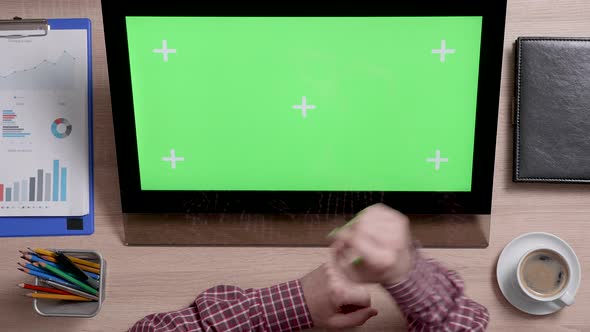 Top View of a Man's Hands Touch the Top Right Corner of a Green Screen on Touch Monitor
