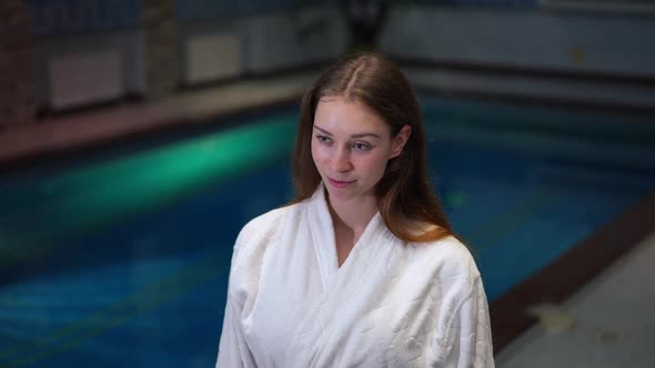 Portrait of Beautiful Slim Young Woman Standing at Pool in Hotel Smiling Looking Away