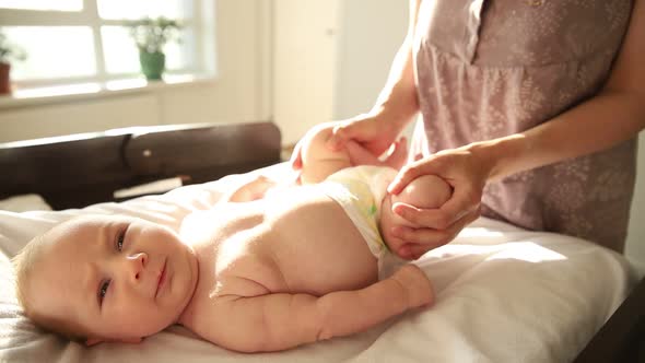 Mother Doing Exercises for Her Newborn Baby - Working with His Legs