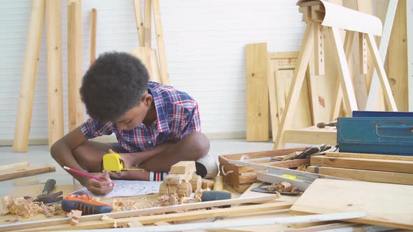 Little boy as a construction worker working with wood and taking measurements making wooden model